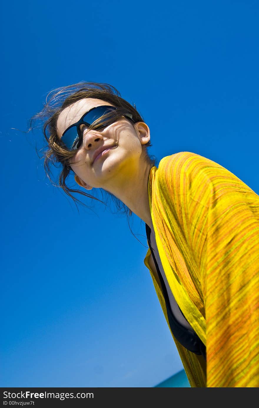 Young woman wrapped in yellow scarf standing day dreamingly on the beach. Young woman wrapped in yellow scarf standing day dreamingly on the beach.