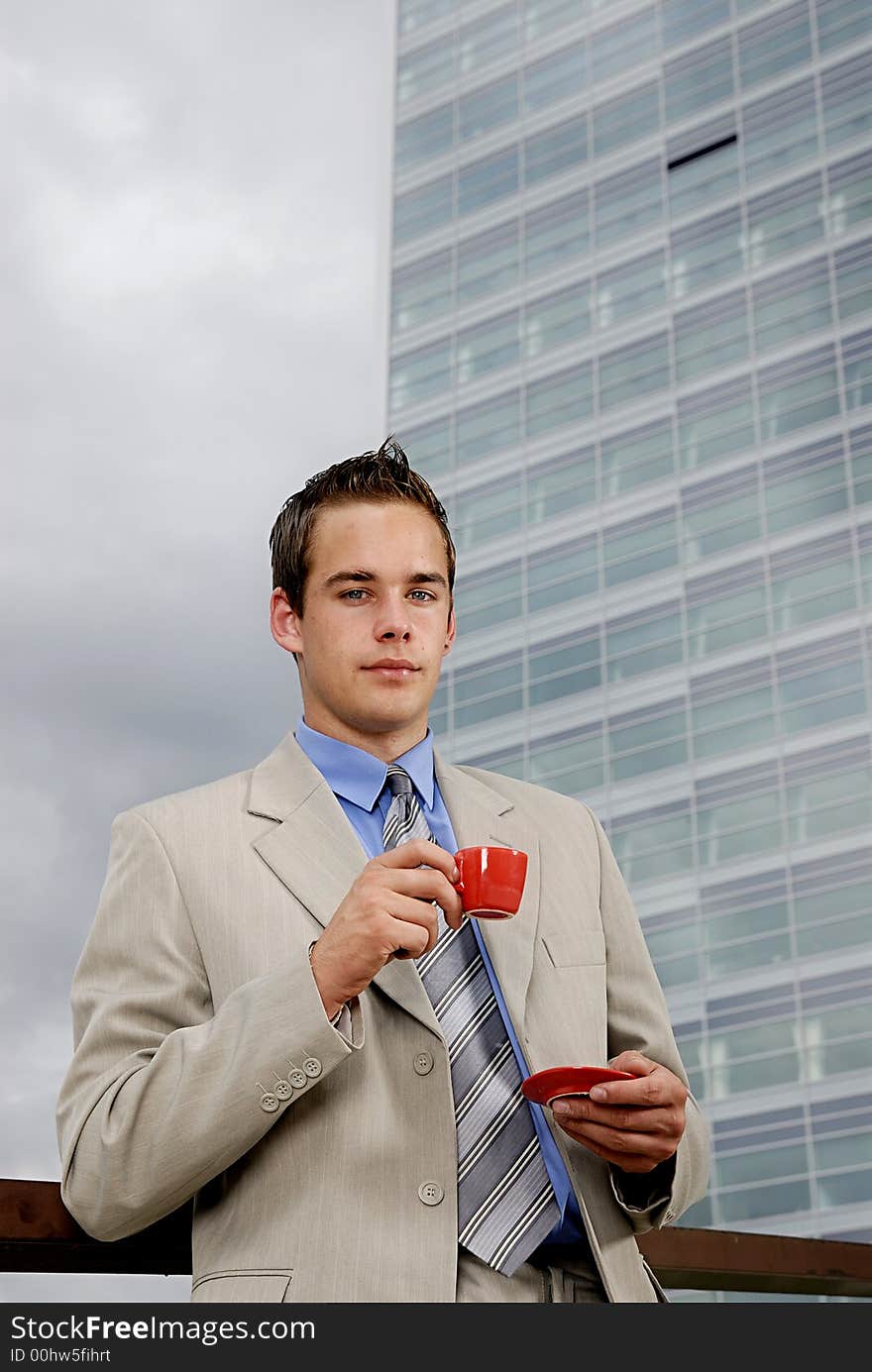 Young businessman having a break and drinking cup of coffee in front of business building. Young businessman having a break and drinking cup of coffee in front of business building.