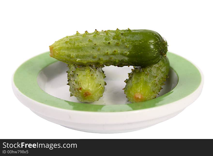 Three little green cucumbers one on one on plate