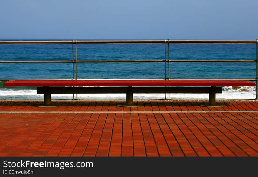 Wooden red bench on the beach with blue sky. Wooden red bench on the beach with blue sky