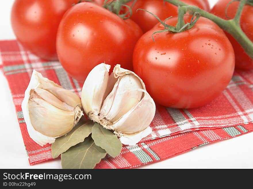 Tomatoes, garlic, bay leaf on white background;