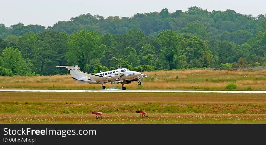 A small private plane touching down on the runway. A small private plane touching down on the runway