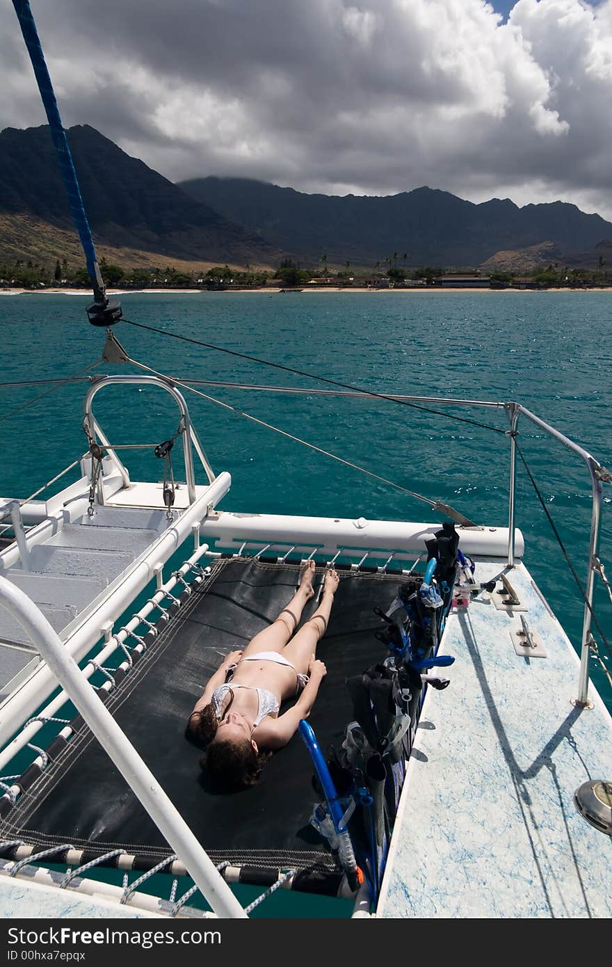 A young teenager sunbathing on the bow of a catamaran