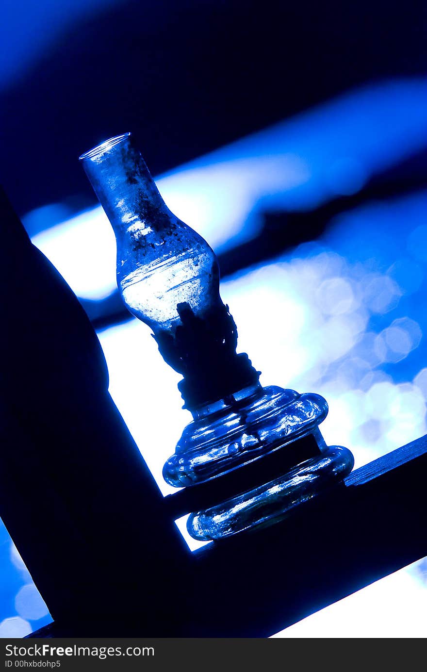 A kerosene lamp seats peacefully before a reflective surface of seawater.