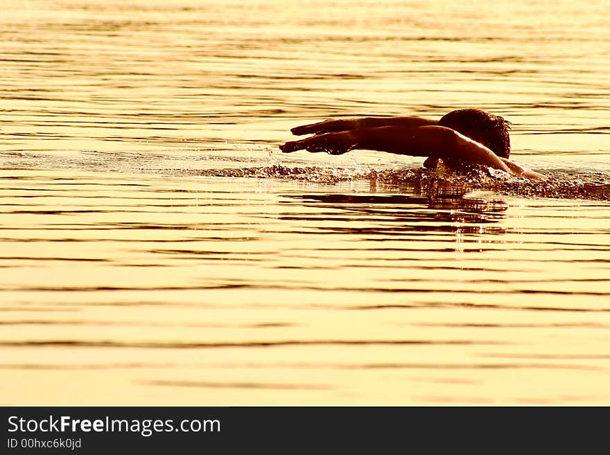 High contrast image of a man diving into lake water during golden sunset, detailed splashes under hands. High contrast image of a man diving into lake water during golden sunset, detailed splashes under hands