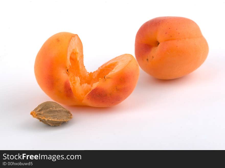 Two apricots and stone on white background