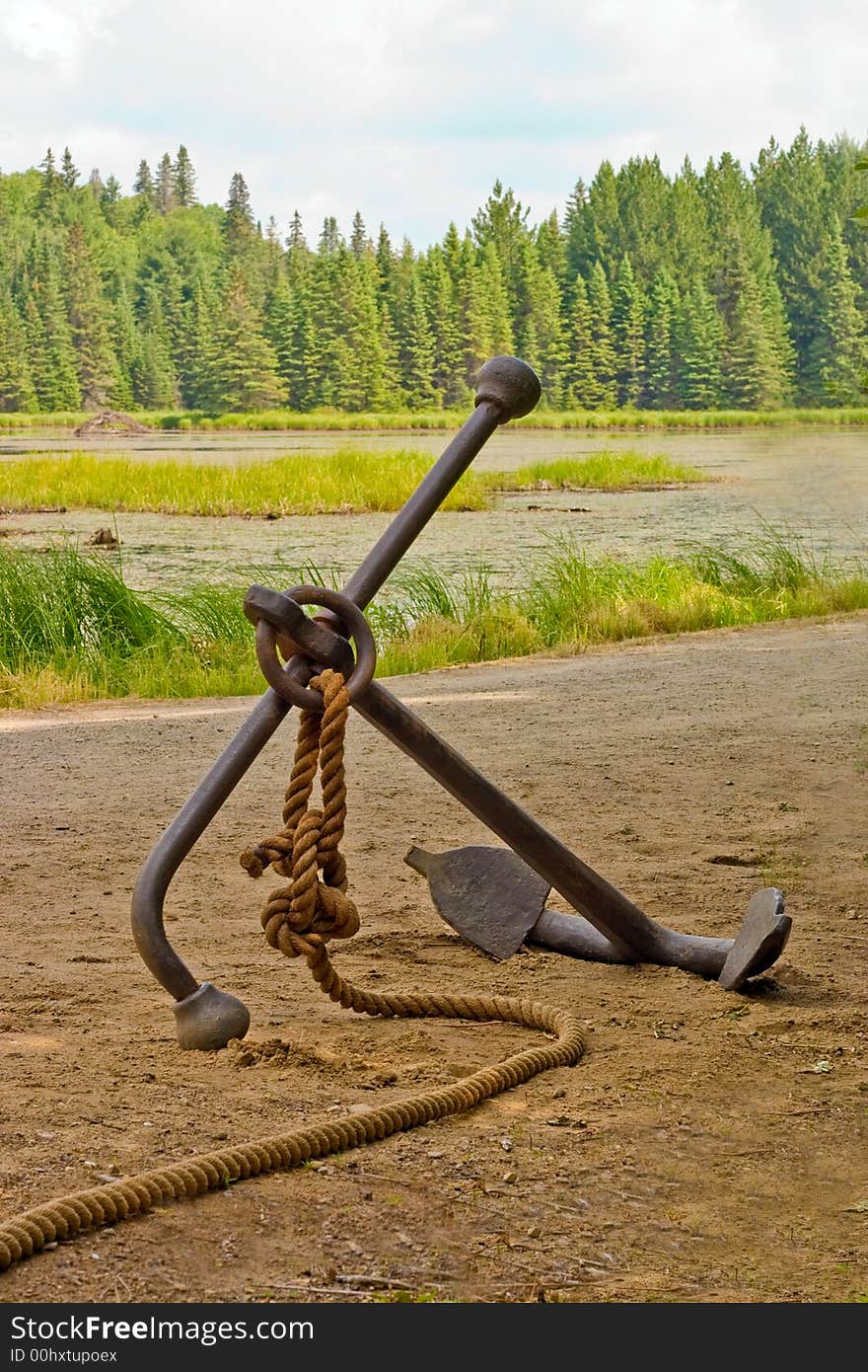 Old heavy anchor with a rope laying by the water. Old heavy anchor with a rope laying by the water