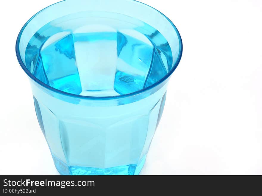 A blue glass of water against white background. A blue glass of water against white background.