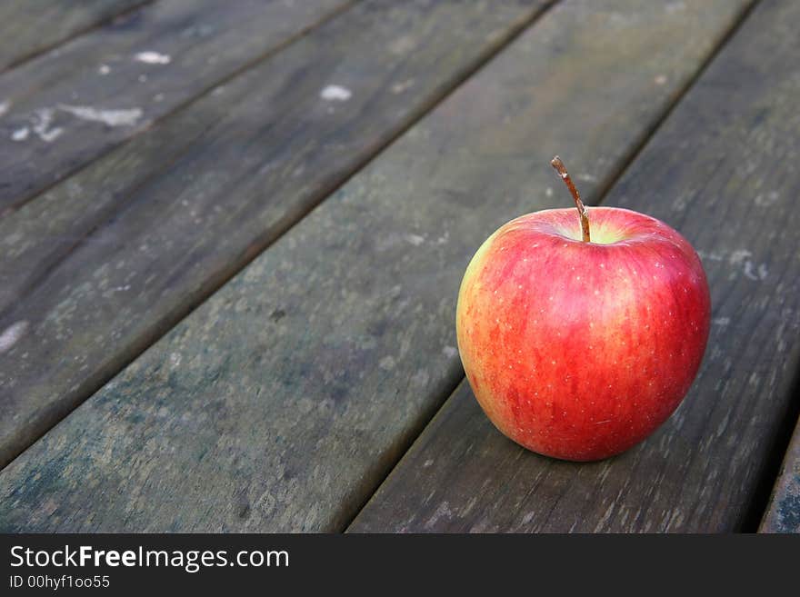 Red apple on a weathered wooden garden or park table