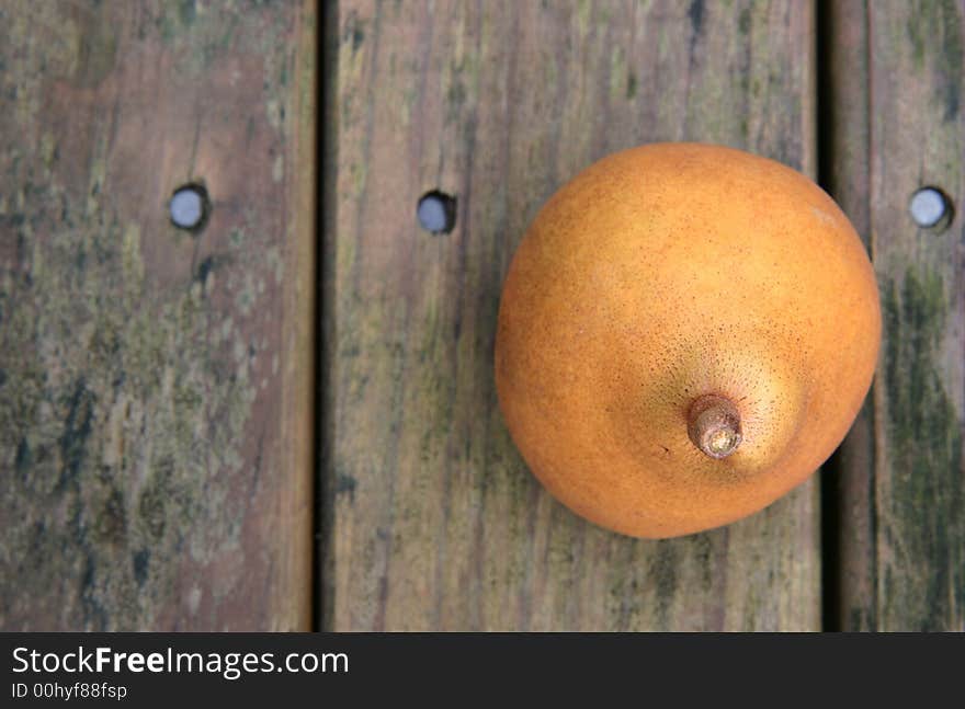 A yellow brown ripe pear on a weathered wooden park table