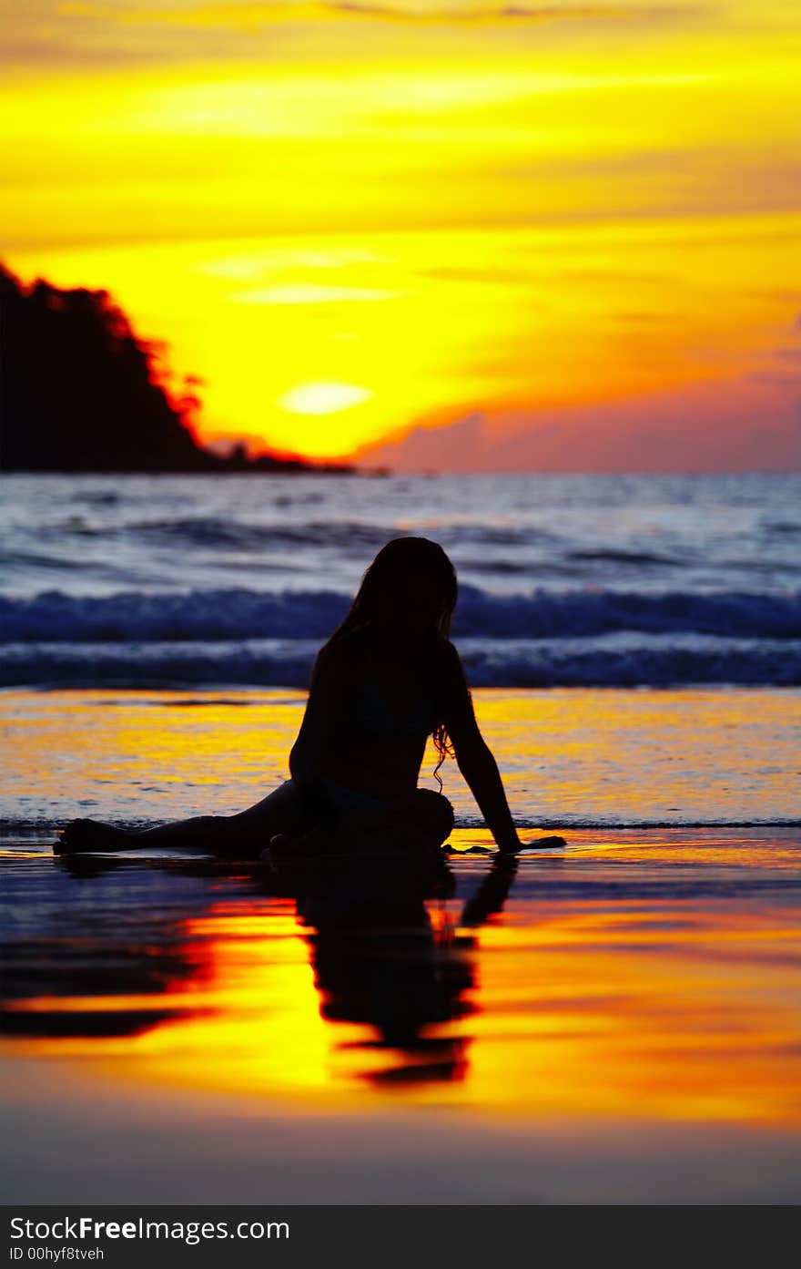 View of a girl lounging on tropical beach during sunset. View of a girl lounging on tropical beach during sunset