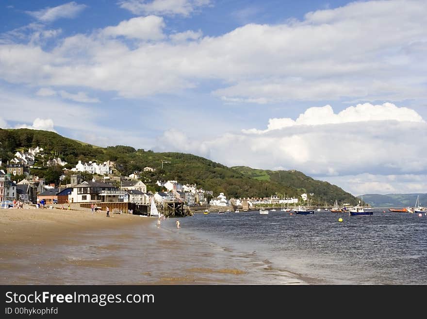 Landscape across beach and estuary towards mountains and clouds. Welsh seaside town with space for text.