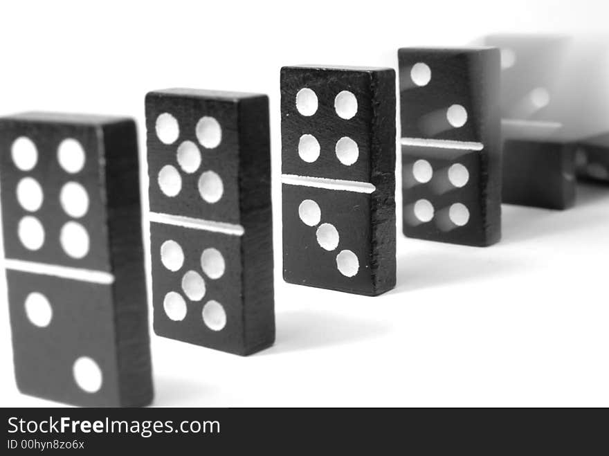 Black domino blocks in line, one is falling. Black domino blocks in line, one is falling