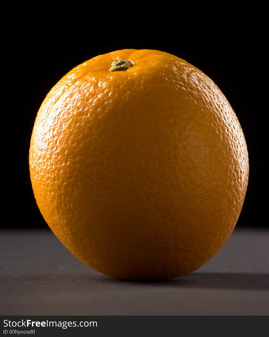 Single orange with a black background