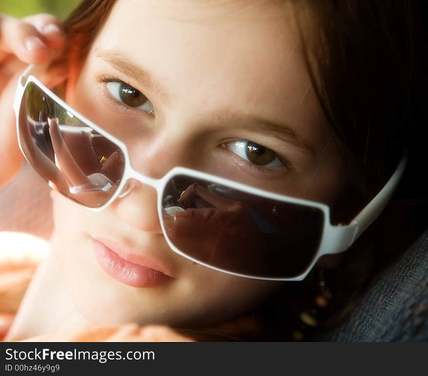 Portrait of an attractive preteen peering over the top of her sunglasses. Portrait of an attractive preteen peering over the top of her sunglasses.