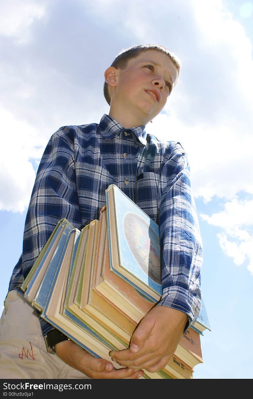 The boy drags a pile of heavy books. The boy drags a pile of heavy books