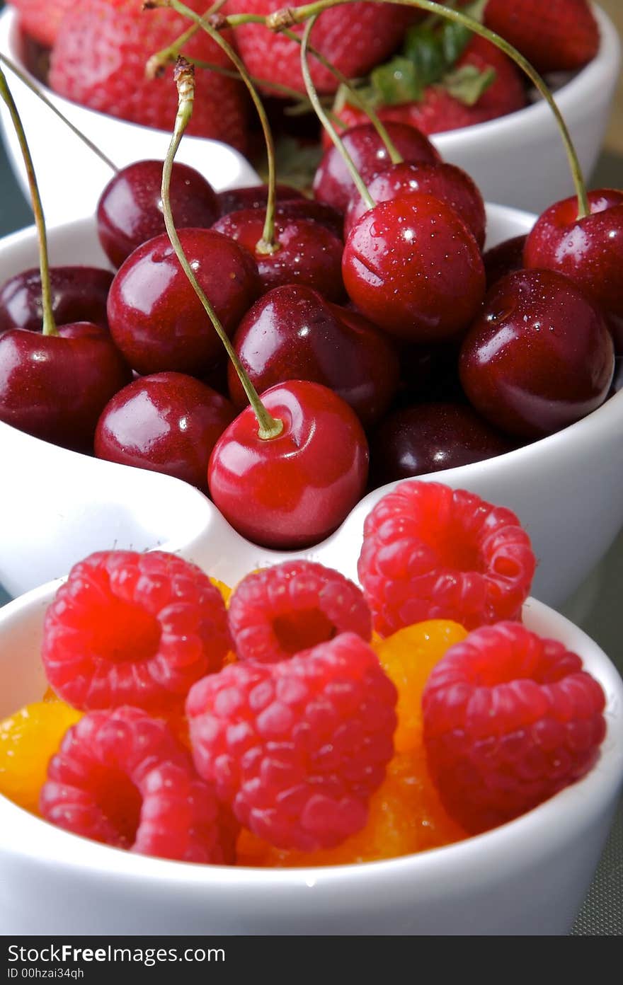 Small white bowls of raspberries, cherries, strawberries, and orange slices. Small white bowls of raspberries, cherries, strawberries, and orange slices.