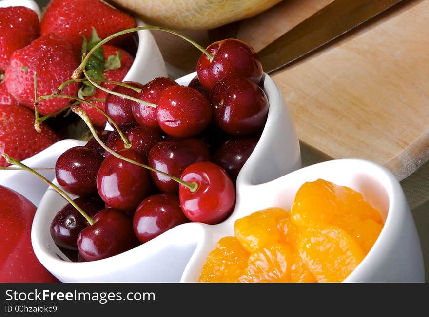 Small white bowls of cherries, strawberries, and orange slices. Small white bowls of cherries, strawberries, and orange slices.