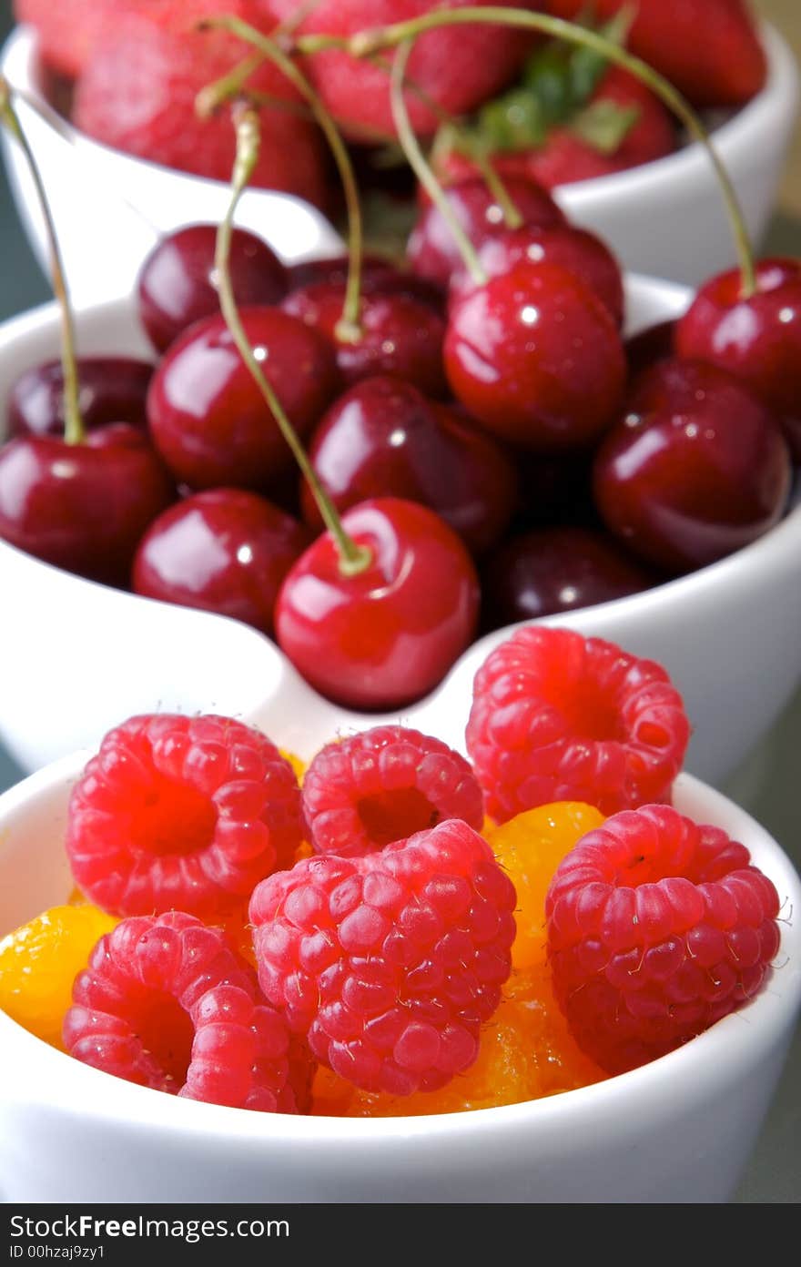 Small white bowls of raspberries, cherries, strawberries, and orange slices. Small white bowls of raspberries, cherries, strawberries, and orange slices.