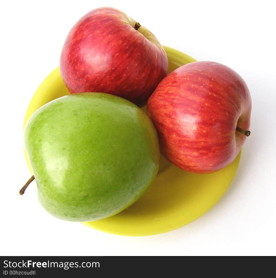 One green and two red apples lay on a yellow plate. One green and two red apples lay on a yellow plate.