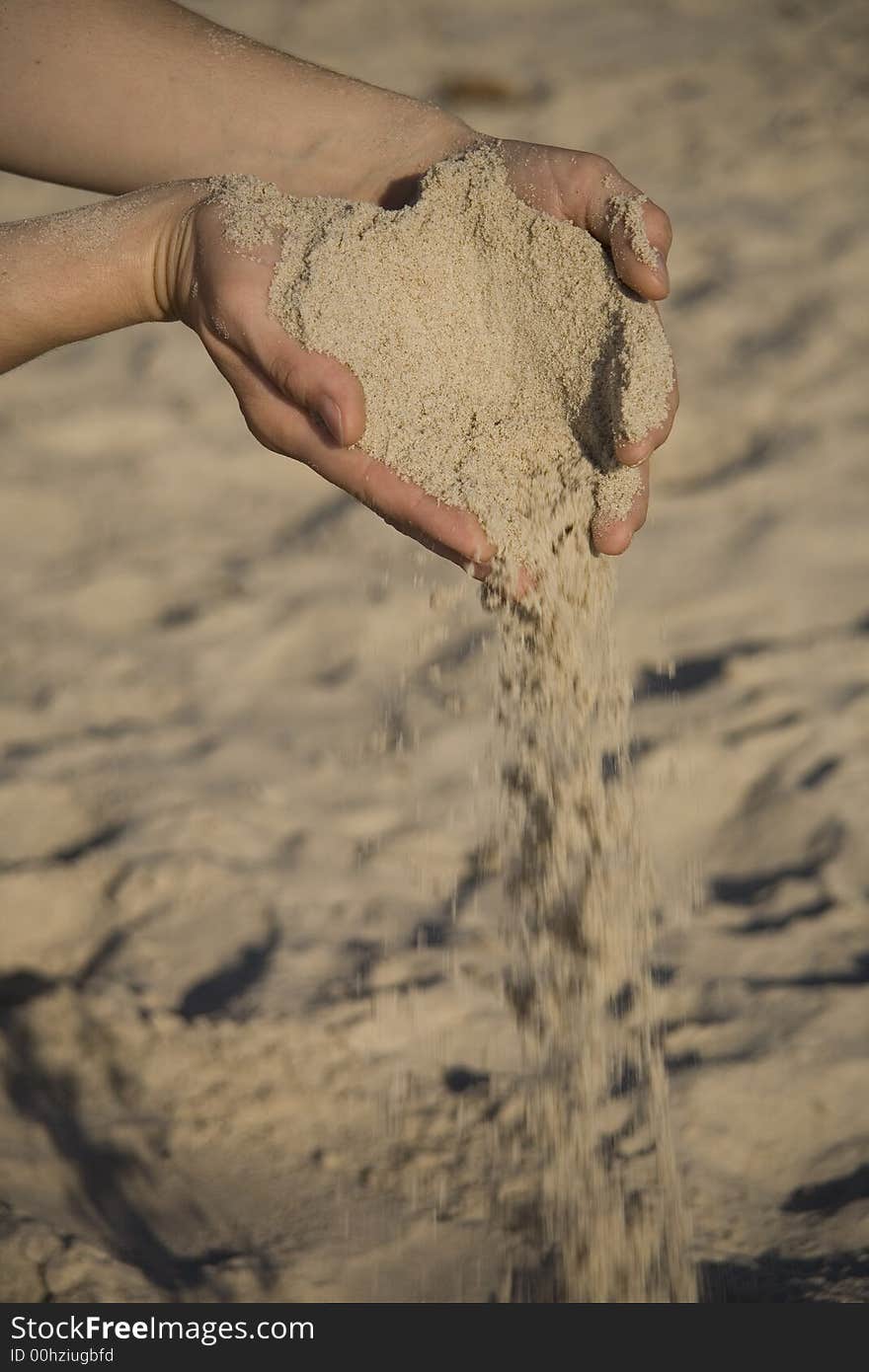 Girl pouring fine sand from two hand on beach