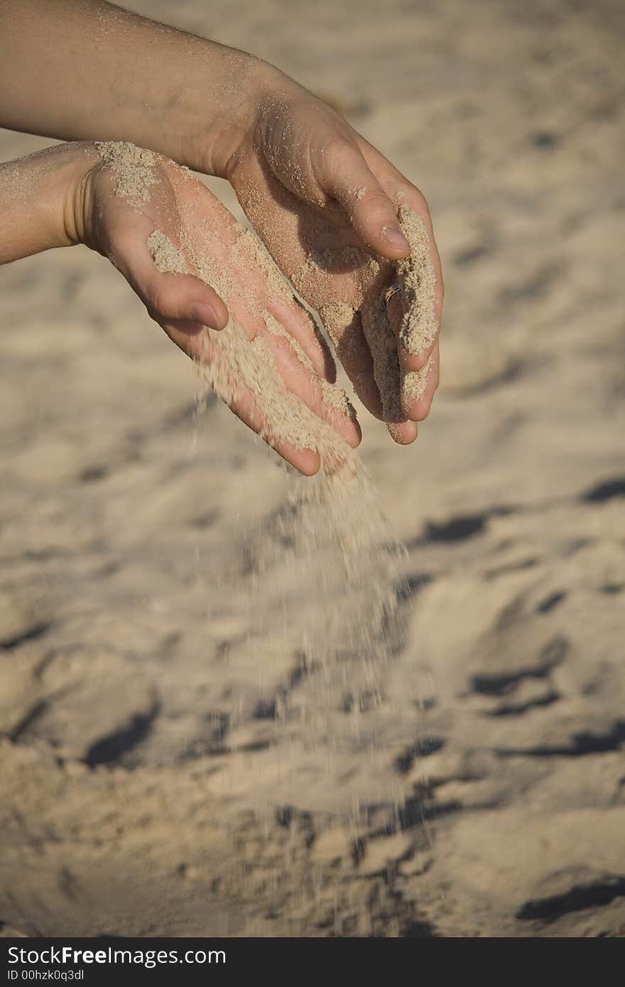 Girl pouring fine sand from two hand on beach