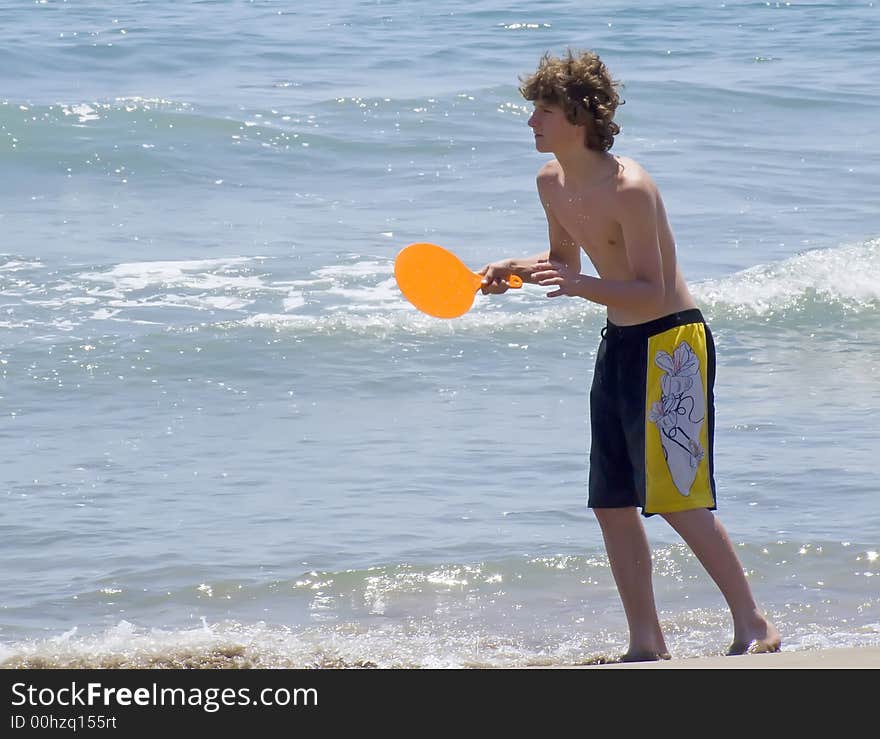 Young man playing beachball at the shore