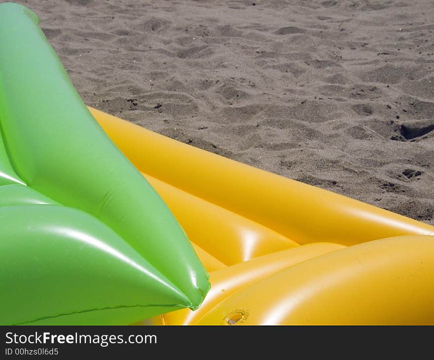 Two colored air mattrasses on the beach