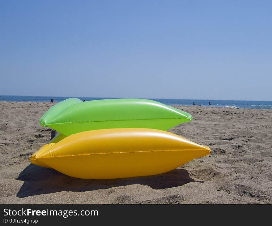 Two colored air mattrasses on the beach