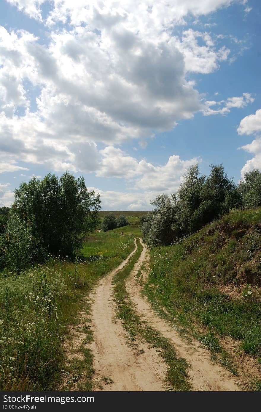 Twisted road in green meadows, rural landscape.