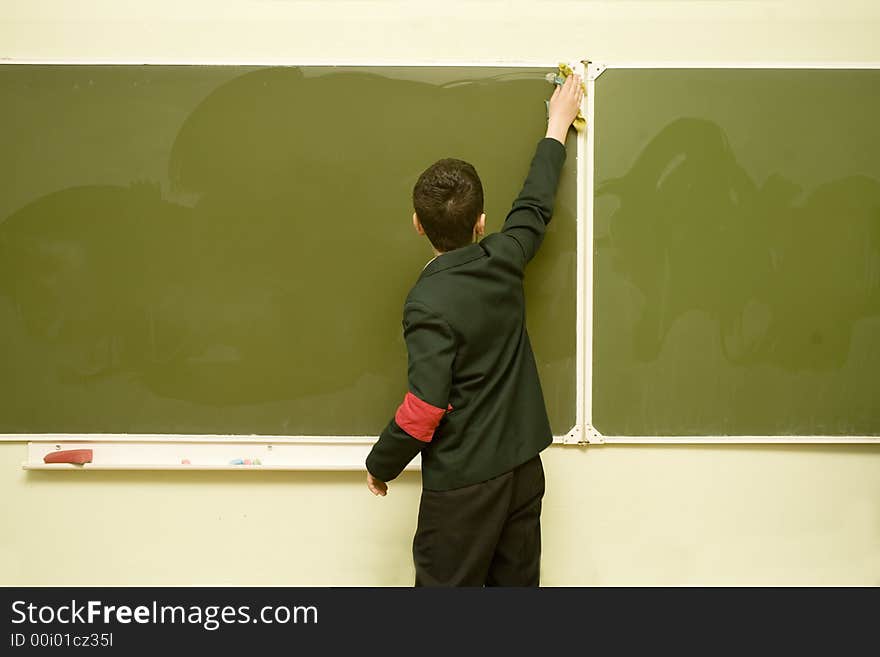 A young pupil is cleaning the blackboard. A young pupil is cleaning the blackboard