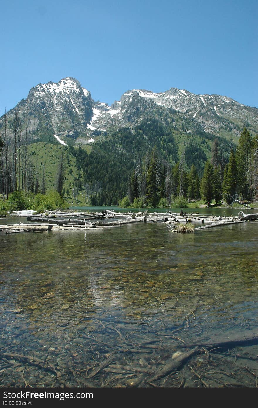 The Tetons mountain range seen across from a shallow but clear body of water. The Tetons mountain range seen across from a shallow but clear body of water.