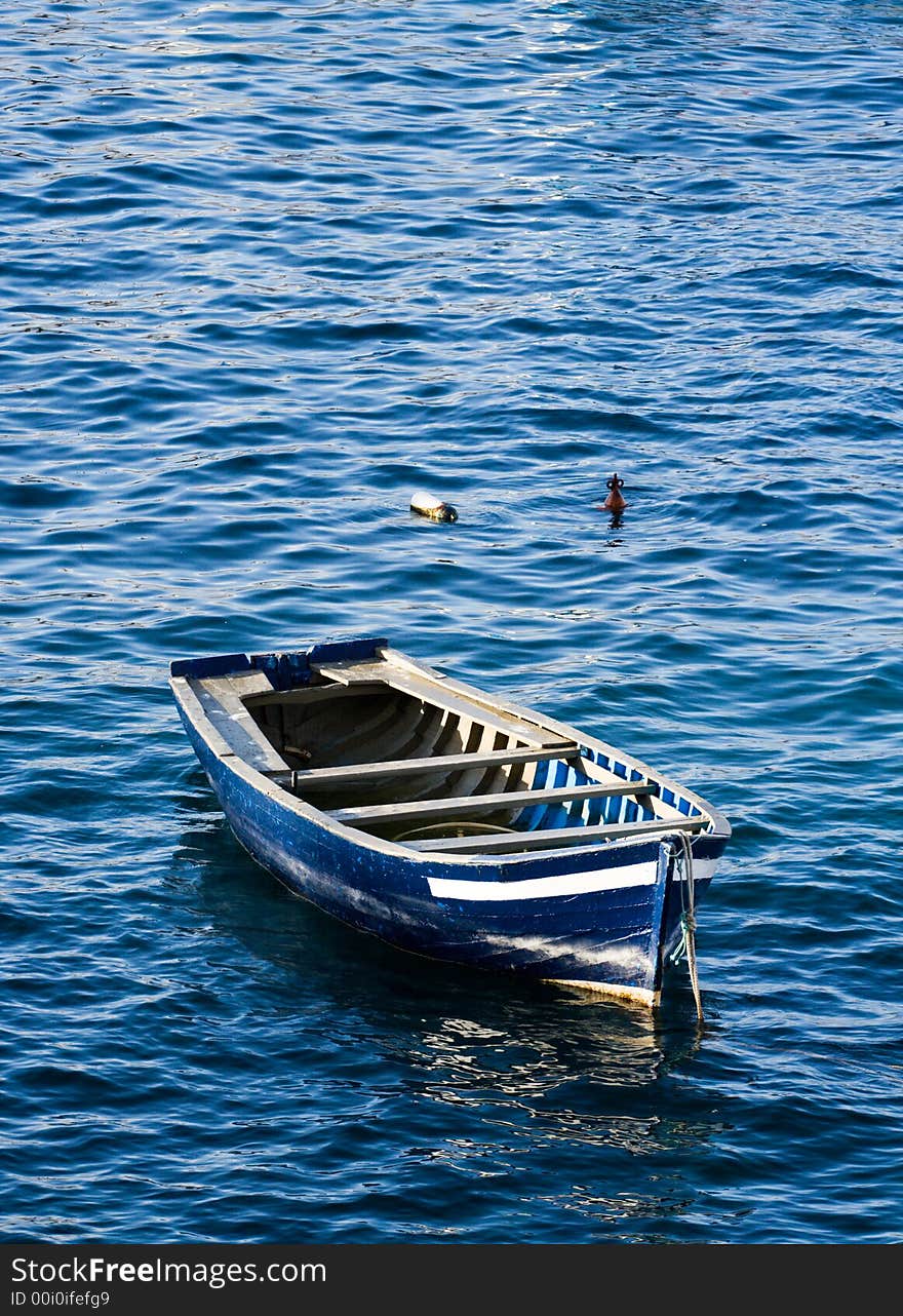 Wooden fishing boat floating on the blue sea. Wooden fishing boat floating on the blue sea