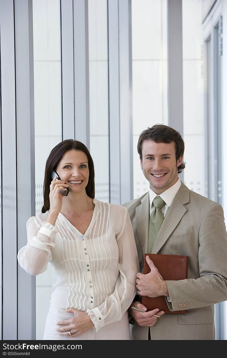 Smiling modern business couple with woman on cell phone