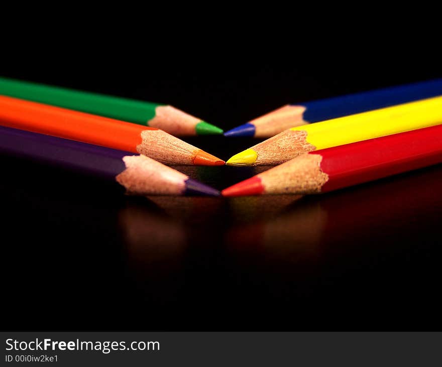 Colored pencils, blue, purple, red, orange, yellow, and green on a black background. Colored pencils, blue, purple, red, orange, yellow, and green on a black background.