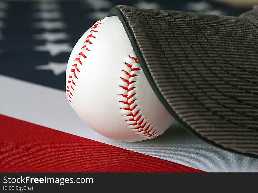 A hat and baseball on top of an American flag. A hat and baseball on top of an American flag.