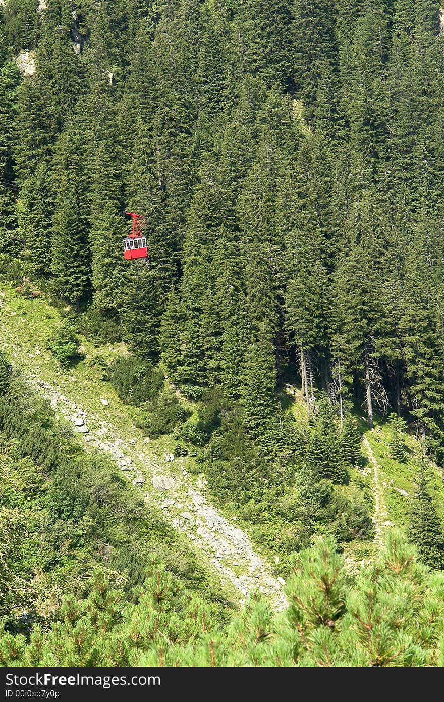 Transportation: a red cable-car cabin through the forest. Transportation: a red cable-car cabin through the forest