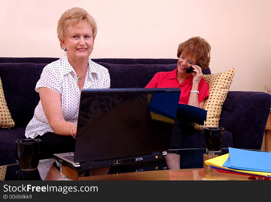 Two mature women working from home in a living room