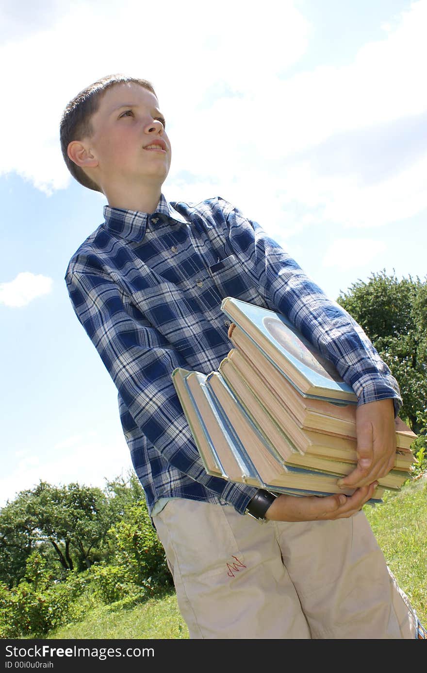 The boy drags a pile of heavy books. The boy drags a pile of heavy books