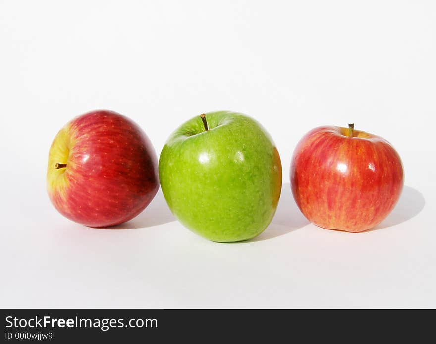 One green and two red apples on a white background. One green and two red apples on a white background.