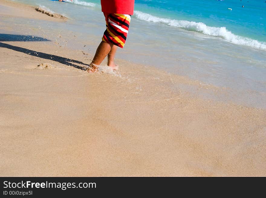 Person walking into the ocean surf from the sandy beach. Person walking into the ocean surf from the sandy beach