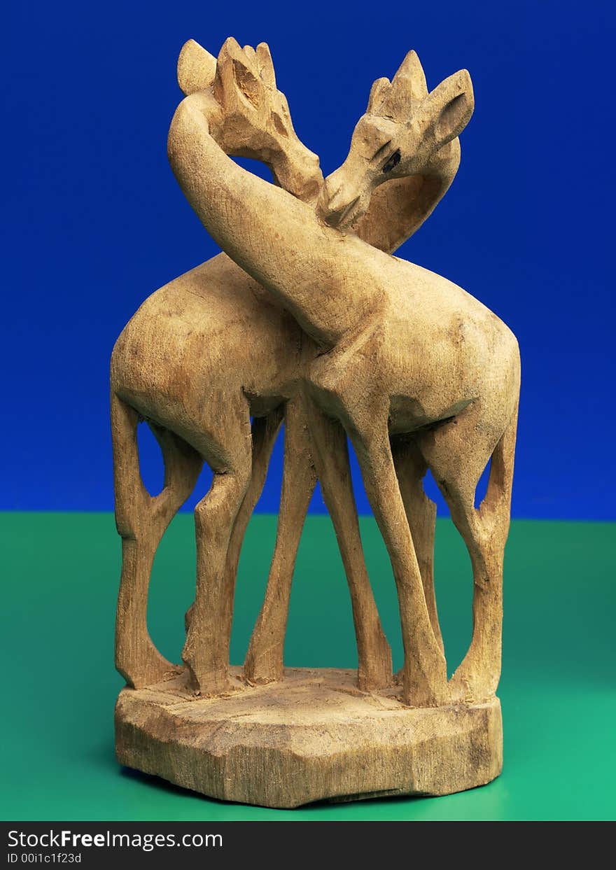 Wooden carving of two giraffes commonly found on roadsides in africa (curios) against a blue and green background. Wooden carving of two giraffes commonly found on roadsides in africa (curios) against a blue and green background.