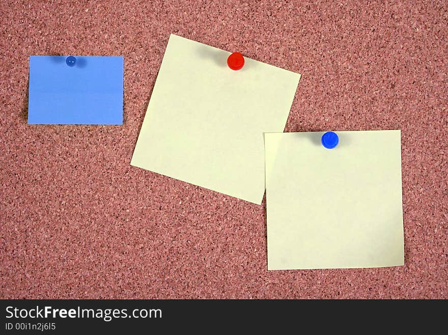 Blue and yellow papers attached to a corkboard. Blue and yellow papers attached to a corkboard.