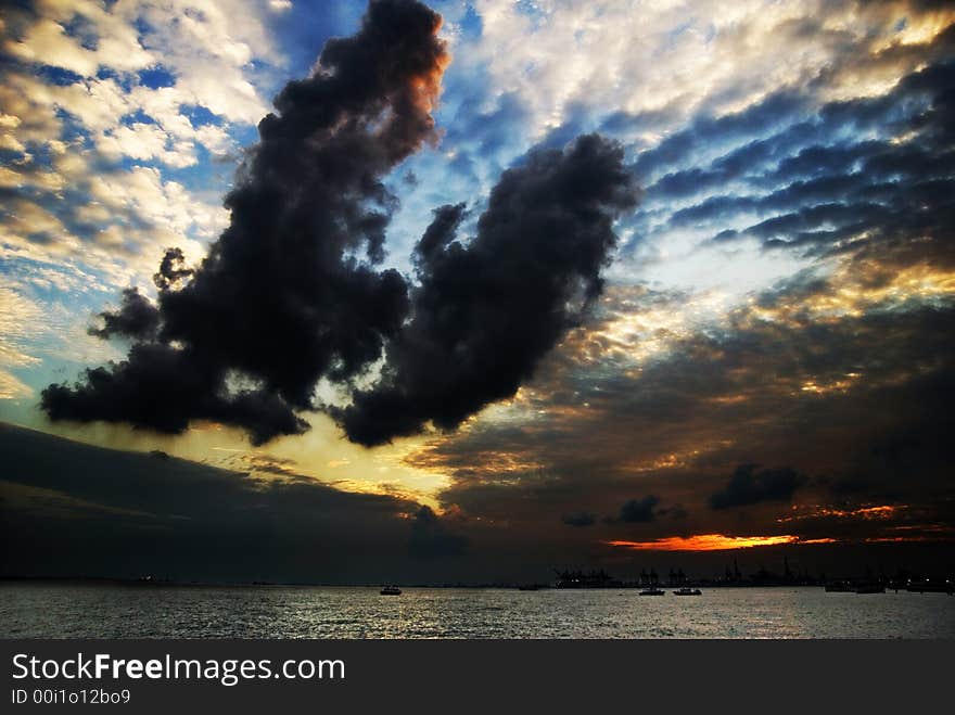 Two huge chunks of dark clouds dominate the foreground of a dramatic sunset. Two huge chunks of dark clouds dominate the foreground of a dramatic sunset