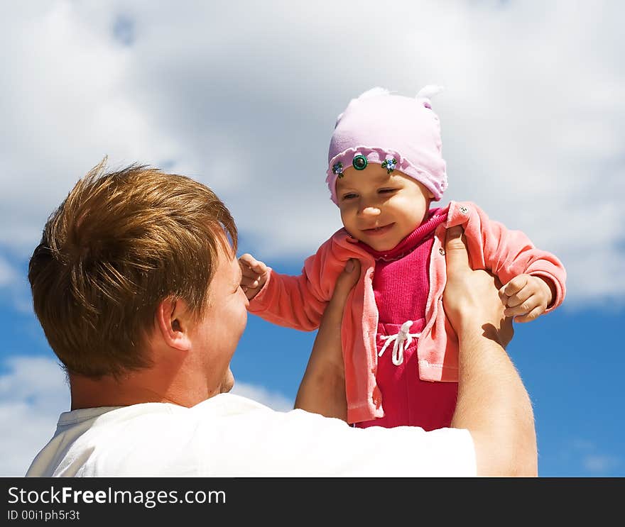 A father throws his infant child into the air. A father throws his infant child into the air