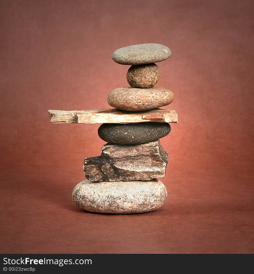 Seven rocks balancing on each other on a brown background. Seven rocks balancing on each other on a brown background