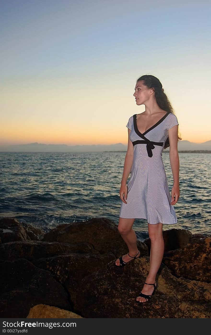 A girl standing on the seabank at the sunset