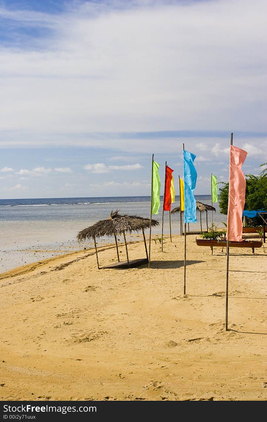 A few flags and a beach hut on the shore. A few flags and a beach hut on the shore