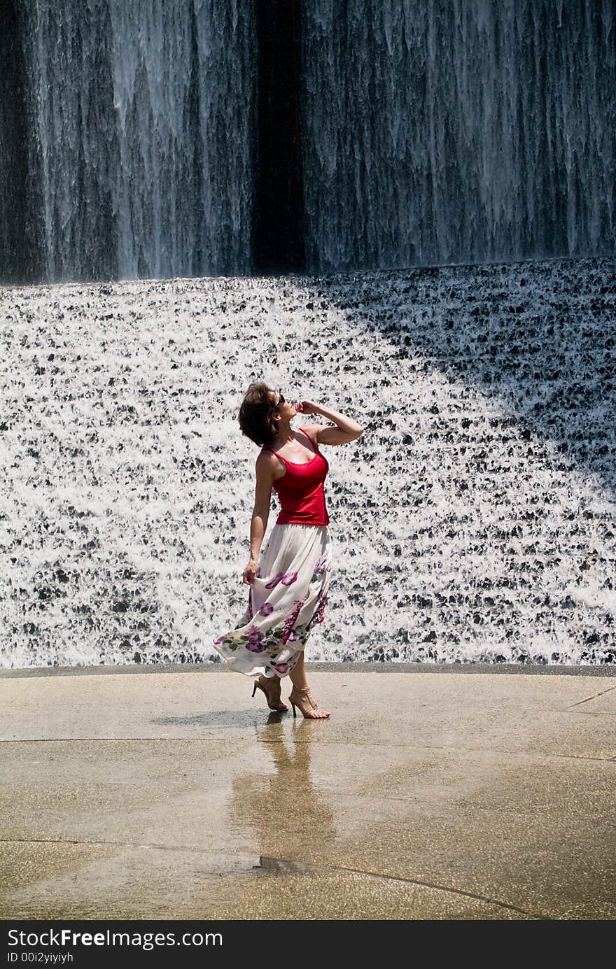 A woman awestruck with the splendor of a cascading waters manmade waterfall. A woman awestruck with the splendor of a cascading waters manmade waterfall