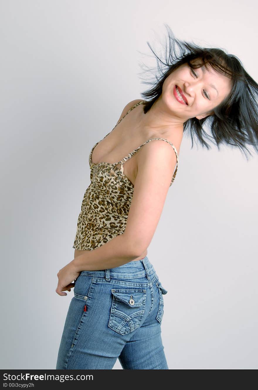 A young, sexy, and attractive Asian woman in jeans and bustier, with her hair blowing in the wind. A young, sexy, and attractive Asian woman in jeans and bustier, with her hair blowing in the wind.